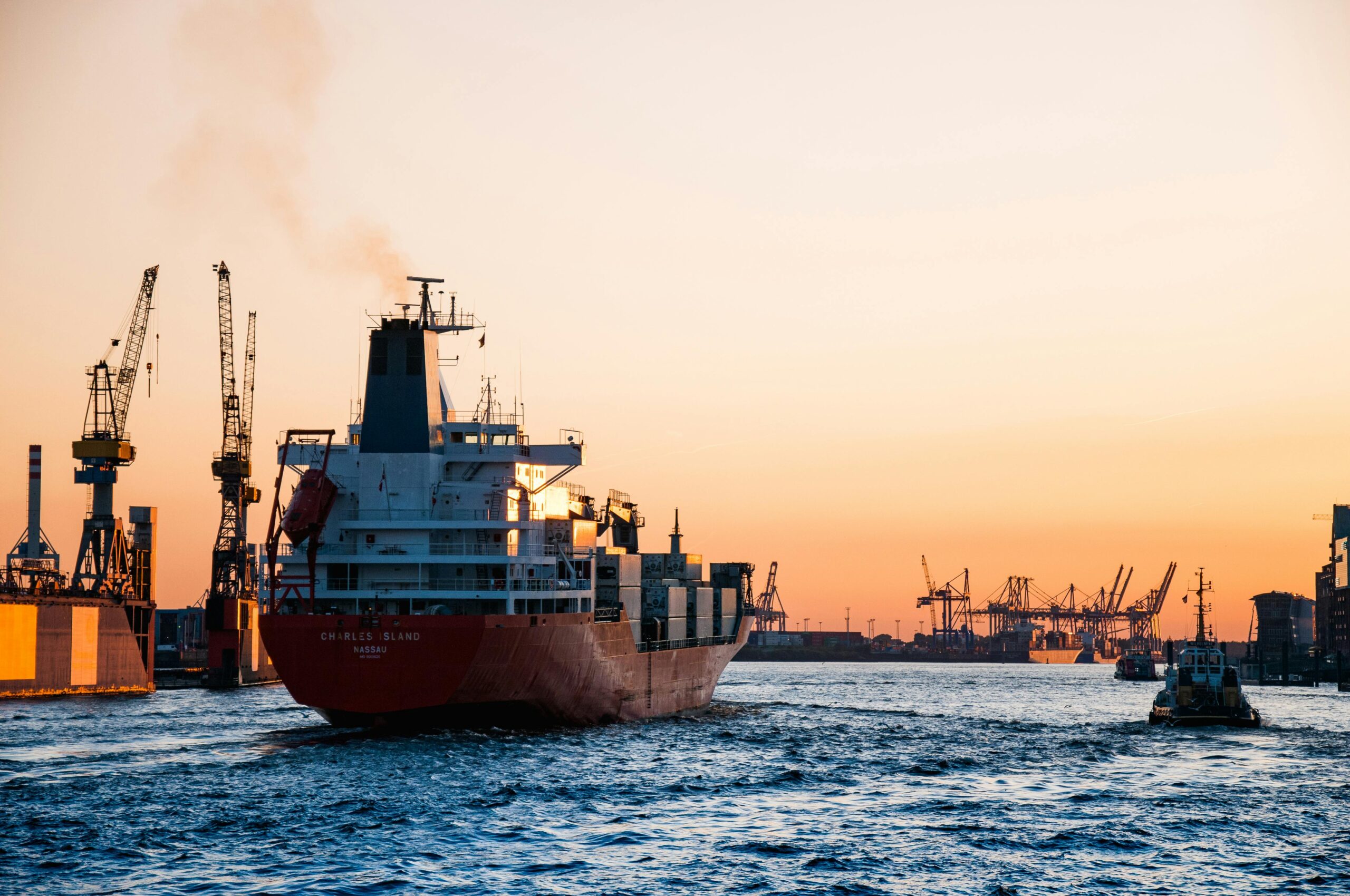 Stunning sunset view of cargo ships and cranes at the Port of Hamburg, epitomizing global trade and logistics.